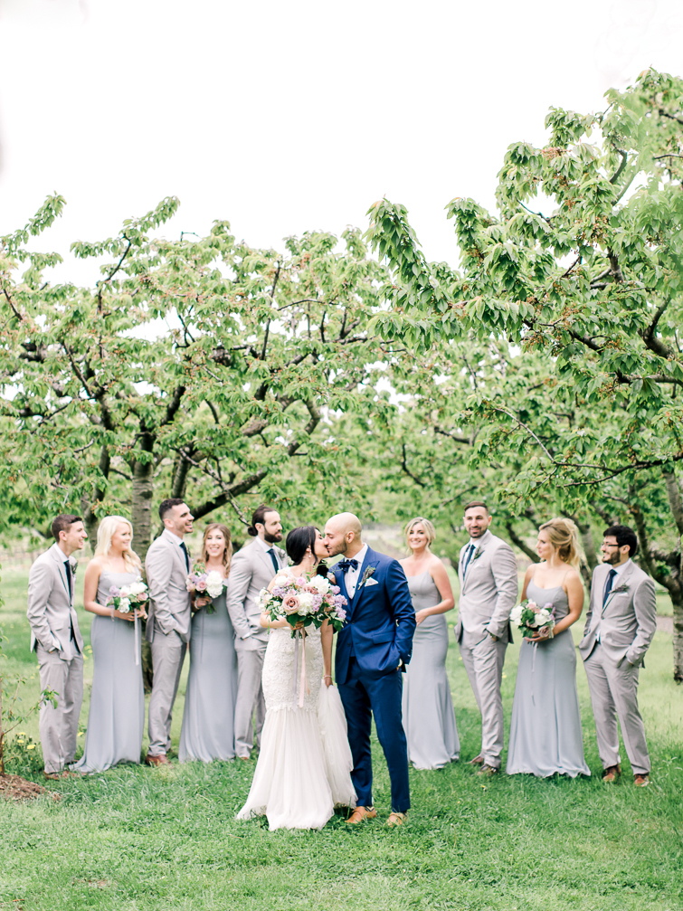 photo of bride and groom kissing with bridal party at kurtz orchards