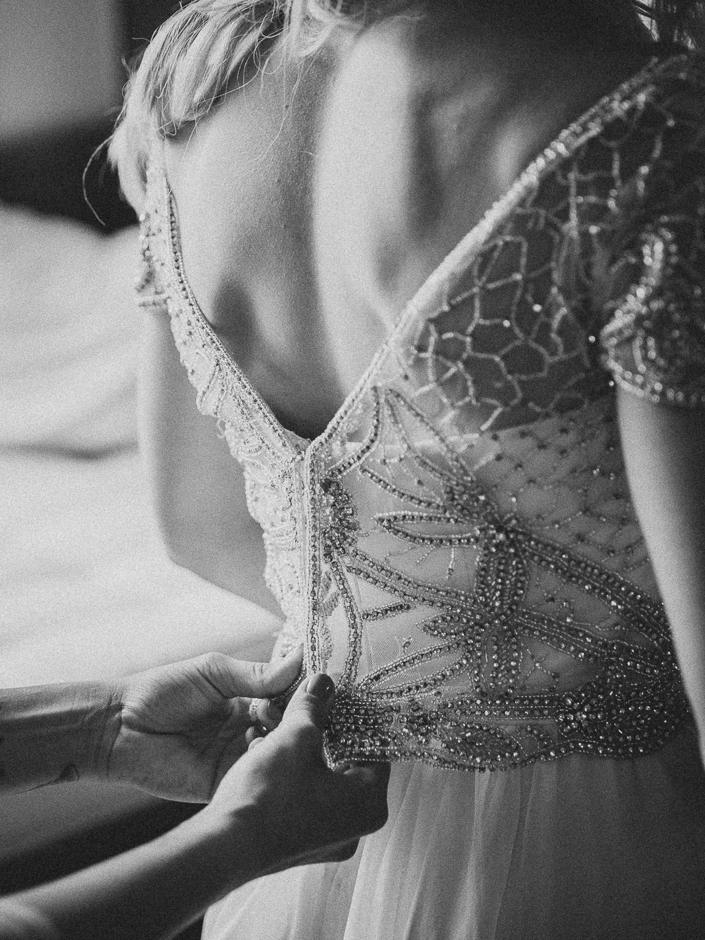 detail shot of bride's lacy dress being done up