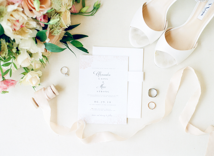 bright and airy layflat of bride's wedding invitations, bouquet and shoes photographed on film