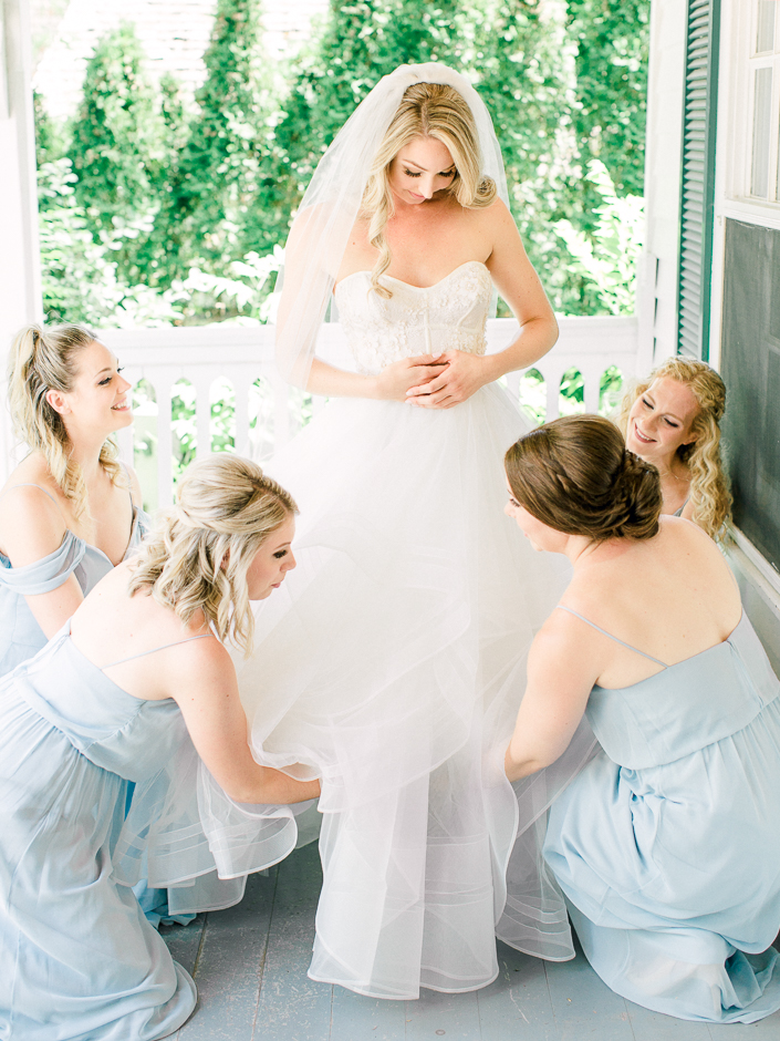 bridesmaids helping bride get dressed at the doctor's house bridal suite